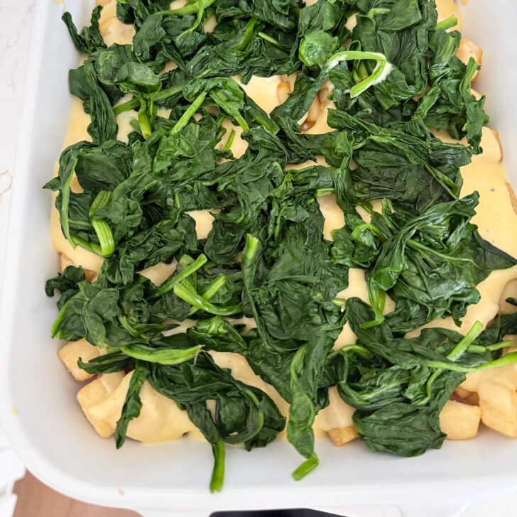 Wilted spinach added to the casserole dish.