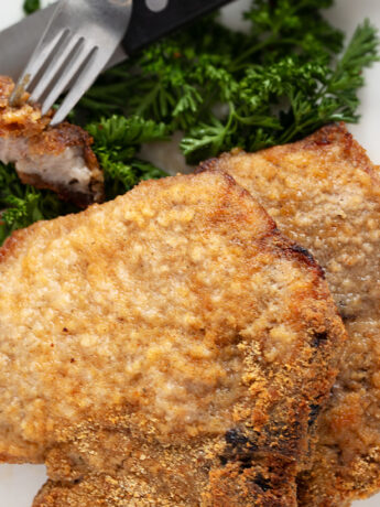 Pork chops coated in homemade shake and bake on a plate.