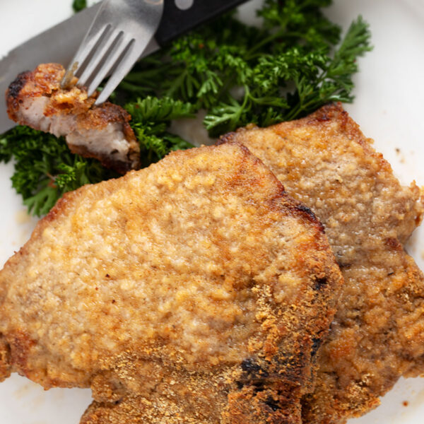 Pork chops coated in homemade shake and bake on a plate.
