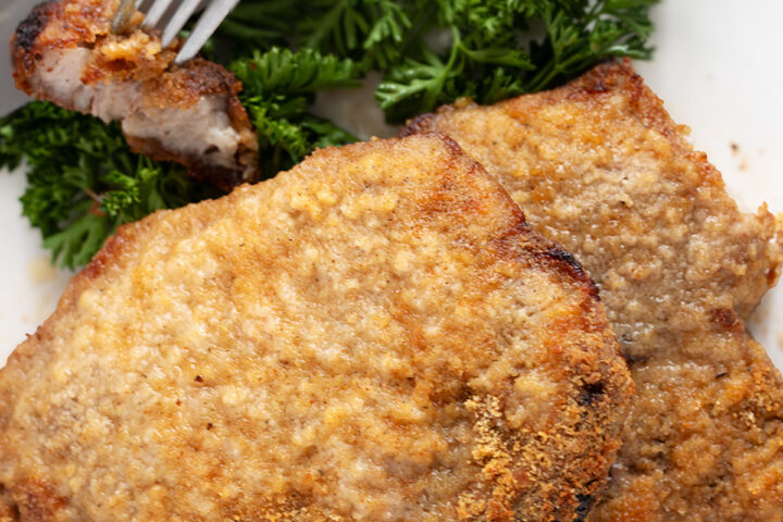 Pork chops coated in homemade shake and bake on a plate.