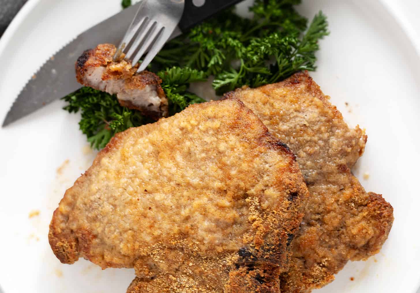 Pork chops coated in homemade shake and bake on a plate.