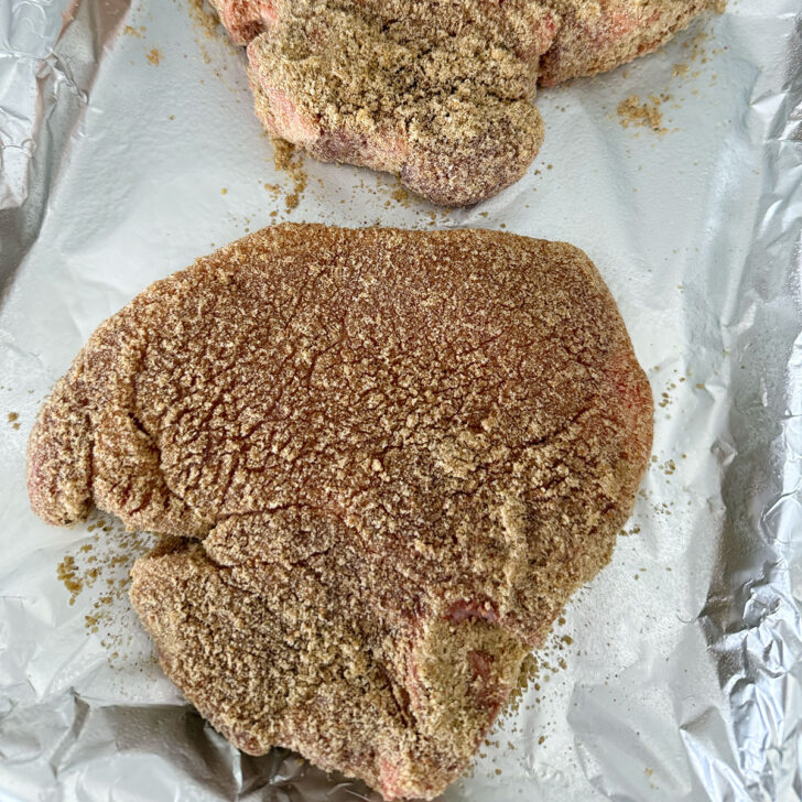 Pork chops with homemade shake and bake on a foil-lined baking sheet.