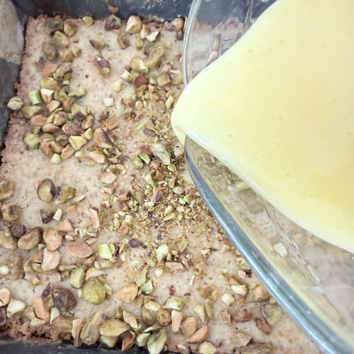 Pouring the lemon filling over the pistachios on top of the base.