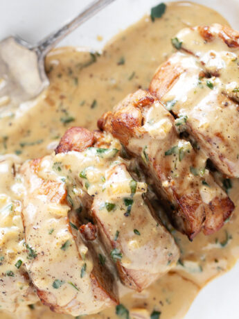 Pork tenderloin medallions on a plate with Dijon sauce.
