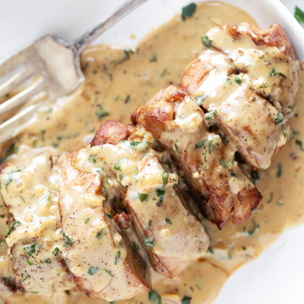 Pork tenderloin medallions on a plate with Dijon sauce.