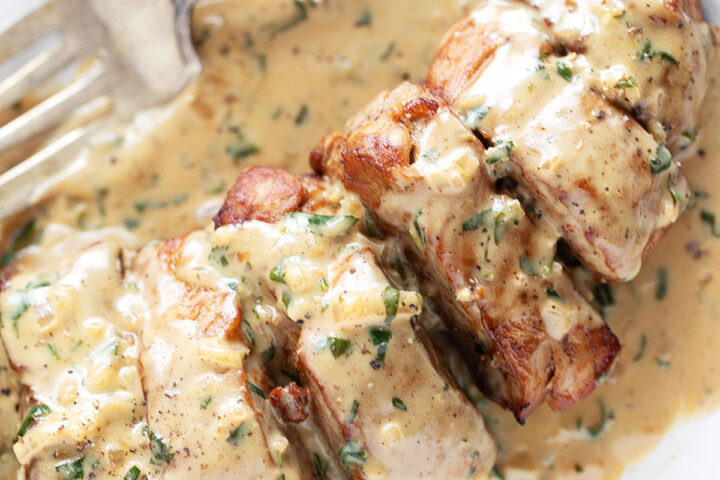Pork tenderloin medallions on a plate with Dijon sauce.