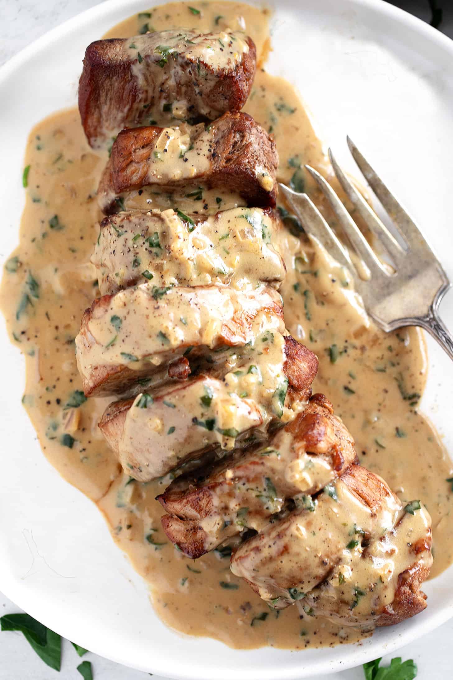 Pork tenderloin medallions on a plate with Dijon sauce.