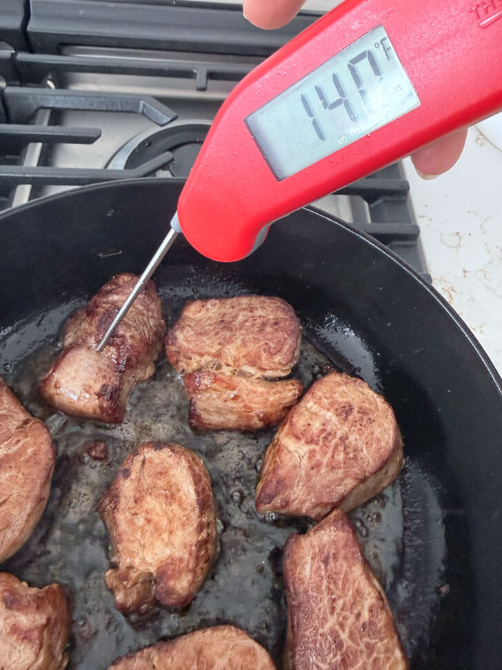 Taking the temperature of the pork with a thermometer.
