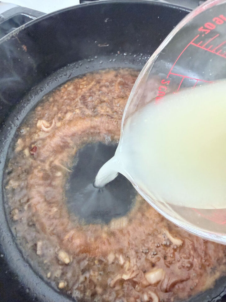 Adding chicken broth to the skillet for the sauce.