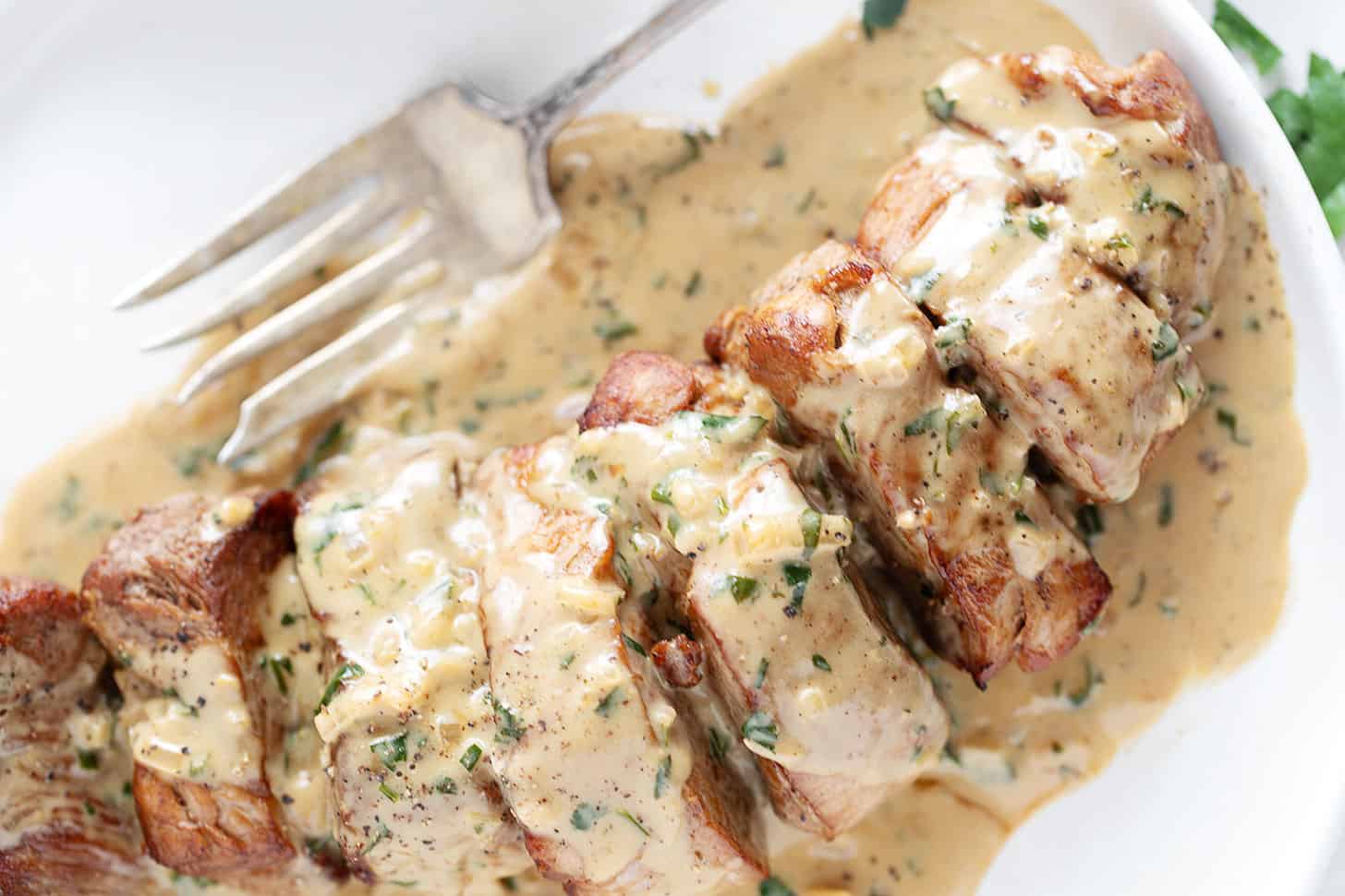 Pork tenderloin medallions on a plate with Dijon sauce.