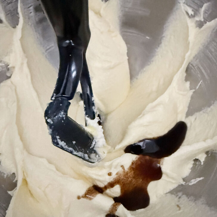 Adding vanilla to the creamed butter and sugar in the mixing bowl.