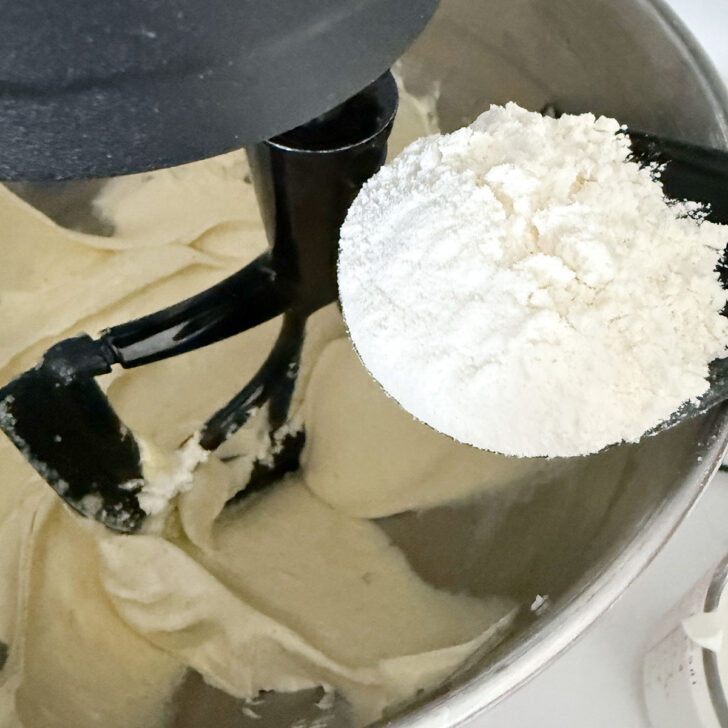 Adding flour to the batter in the mixing bowl.