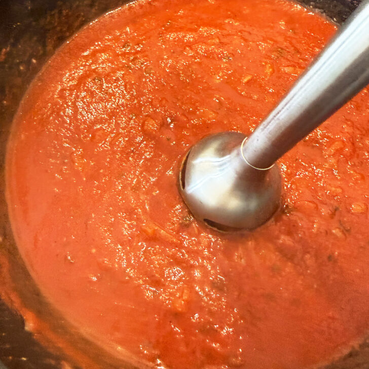 Blending the tomato gravy with an immersion blender.