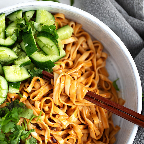 Spicy Málà noodles in a serving bowl with smashed cucumber and cilantro.