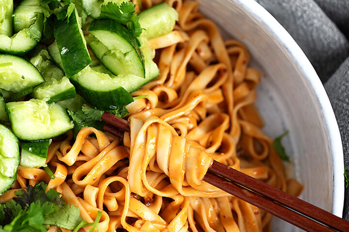 Spicy Málà noodles in a serving bowl with smashed cucumber and cilantro.