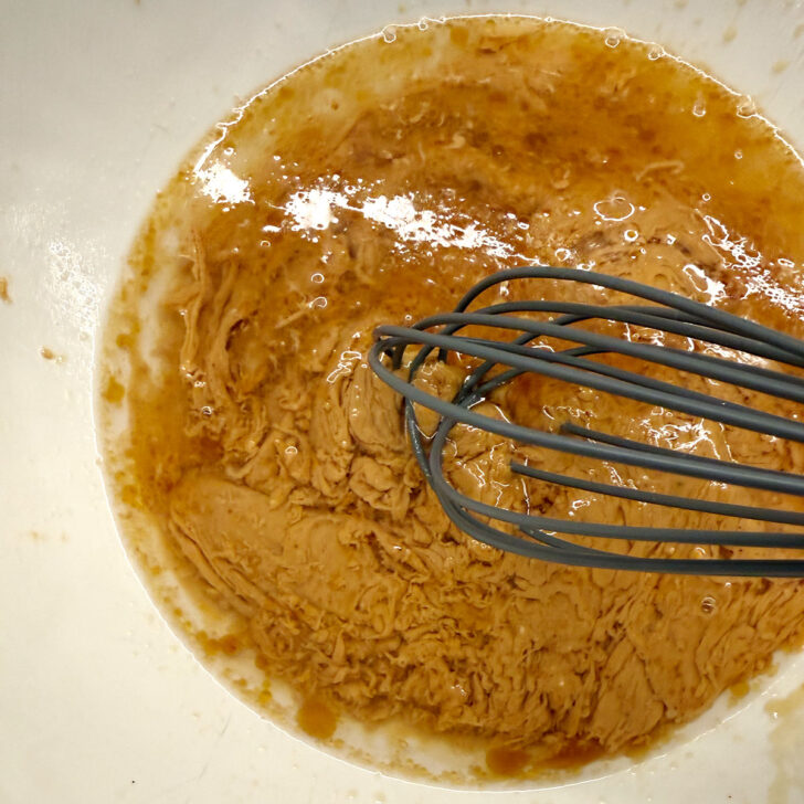 Mixing together the peanut butter and warm water in a small bowl.