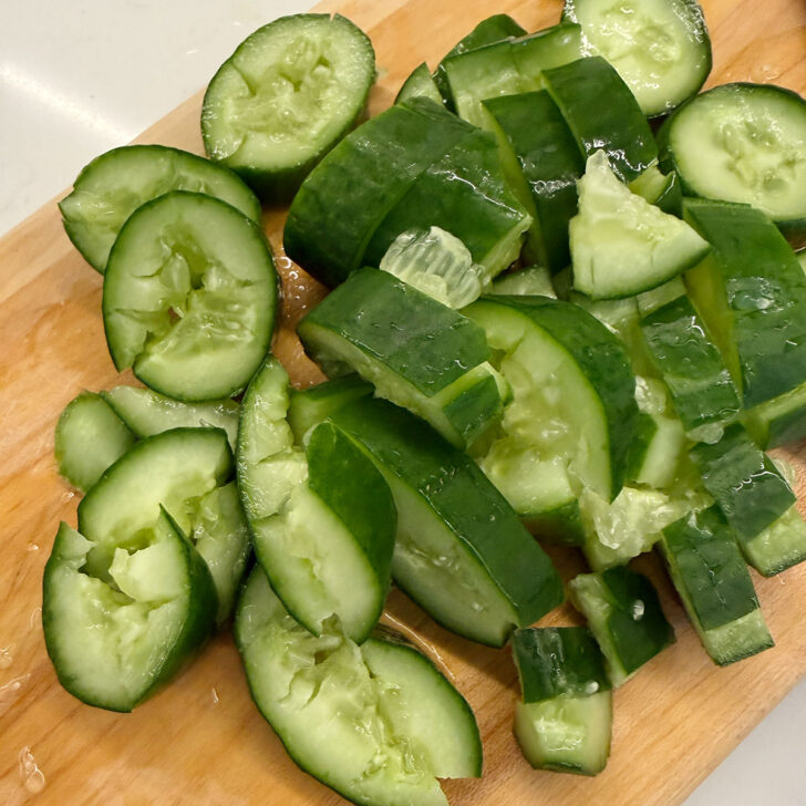 Smashed mini cucumber on a cutting board.