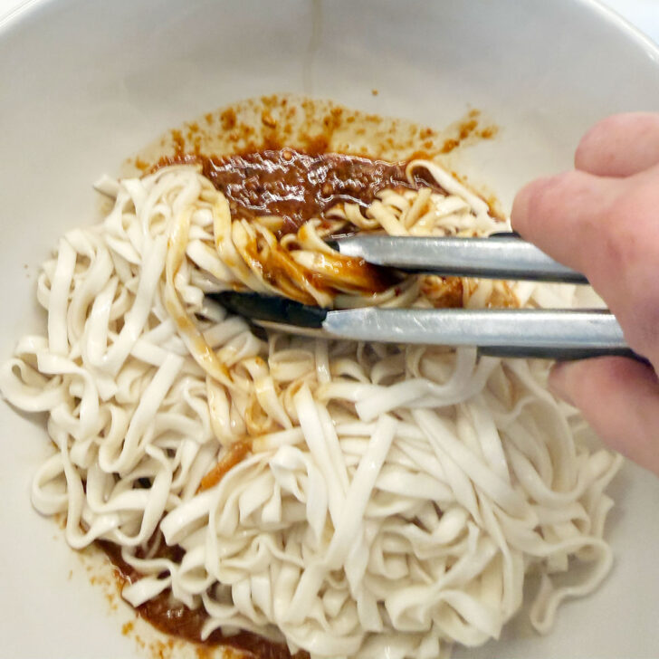 Tossing the drained noodles with the Málà sauce.