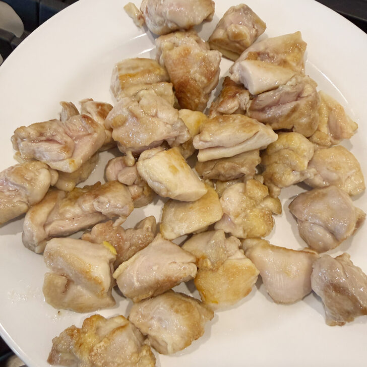 Cooked chicken pieces removed to a plate.