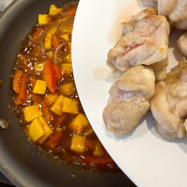 Returning the chicken to the skillet to cook with the sauce.