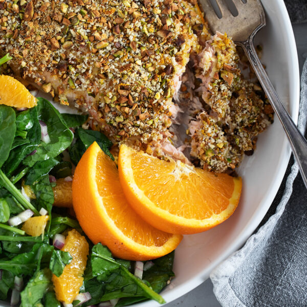 Pistachio-crusted salmon with orange on a plate with an orange salad.