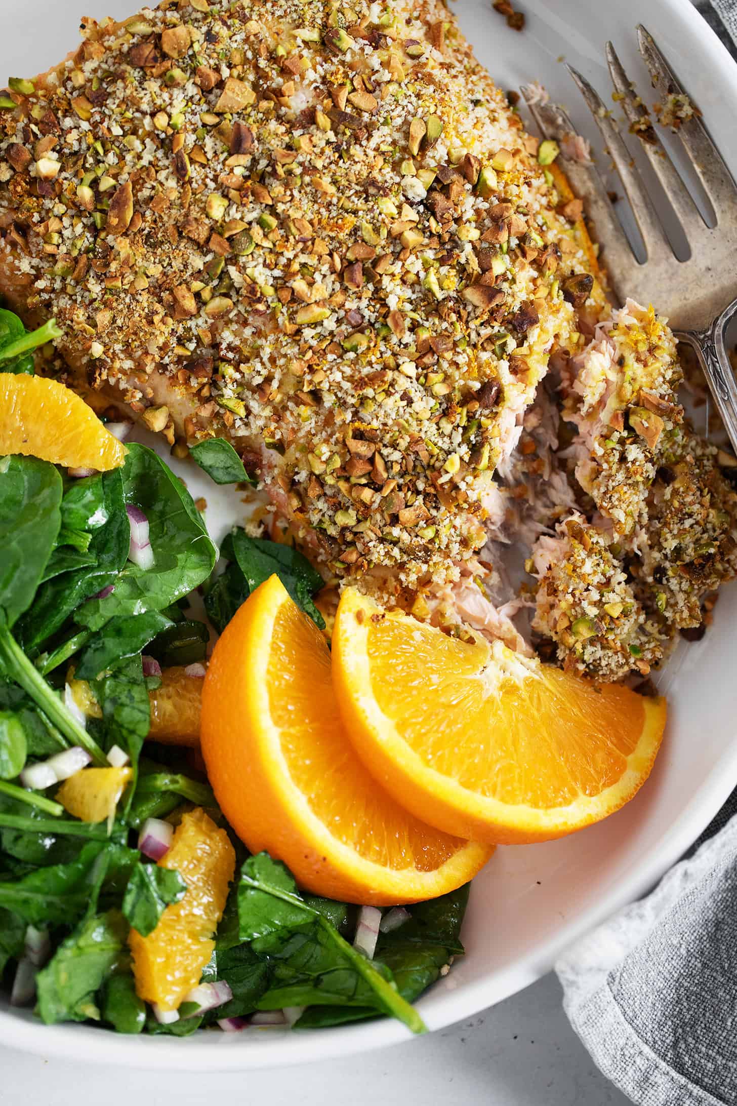 Pistachio-crusted salmon with orange on a plate with an orange salad.