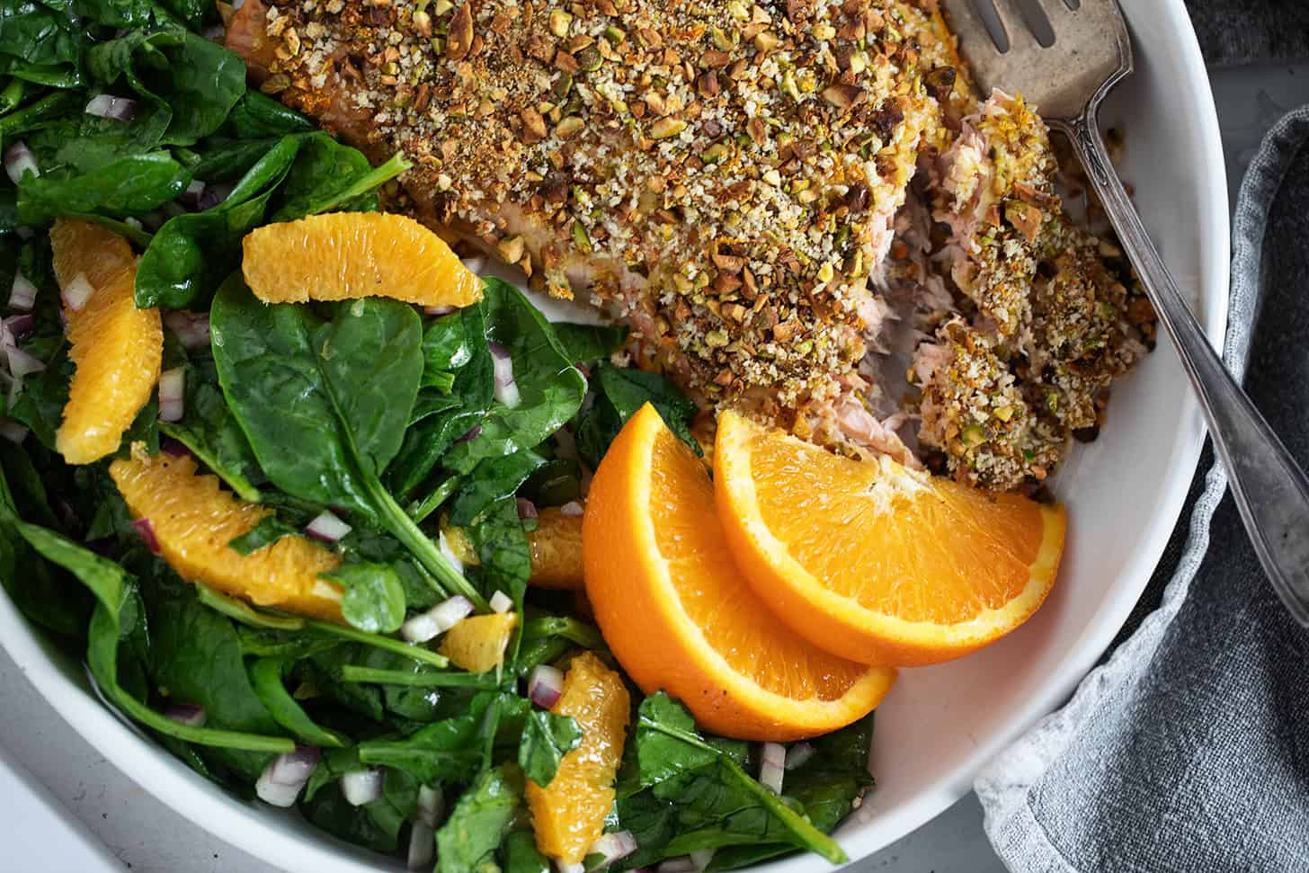 Pistachio-crusted salmon with orange on a plate with an orange salad.