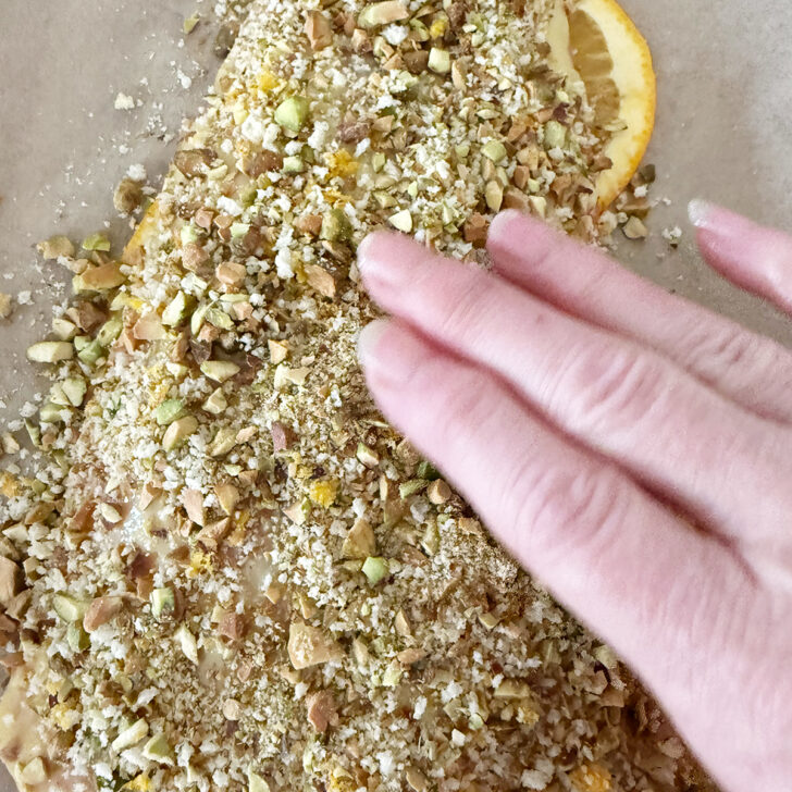 Pressing the pistachio topping onto the salmon.