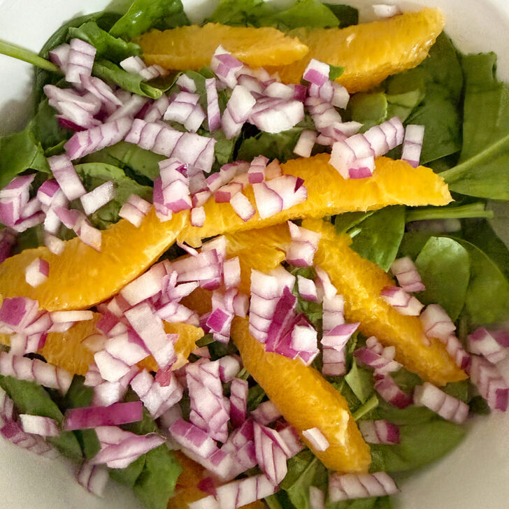 Spinach orange salad ingredients in a bowl.