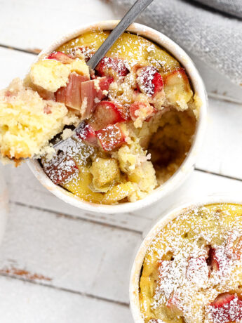 Rhubarb custard cake cups on a serving board with a spoon.