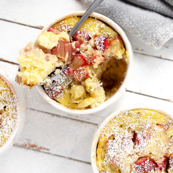 Rhubarb custard cake cups on a serving board with a spoon.