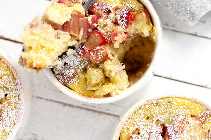 Rhubarb custard cake cups on a serving board with a spoon.