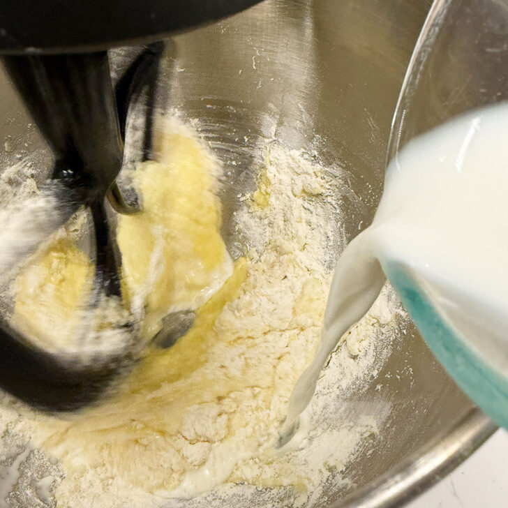 Adding some of the milk to the cake batter.