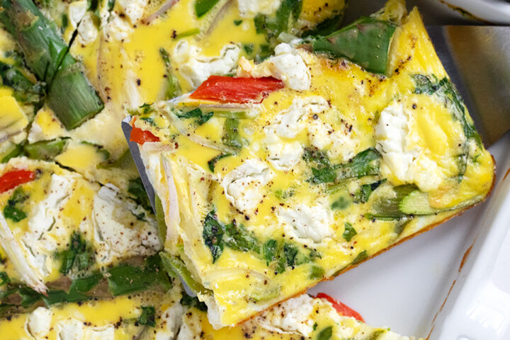 Sheet pan asparagus frittata cut in the pan.