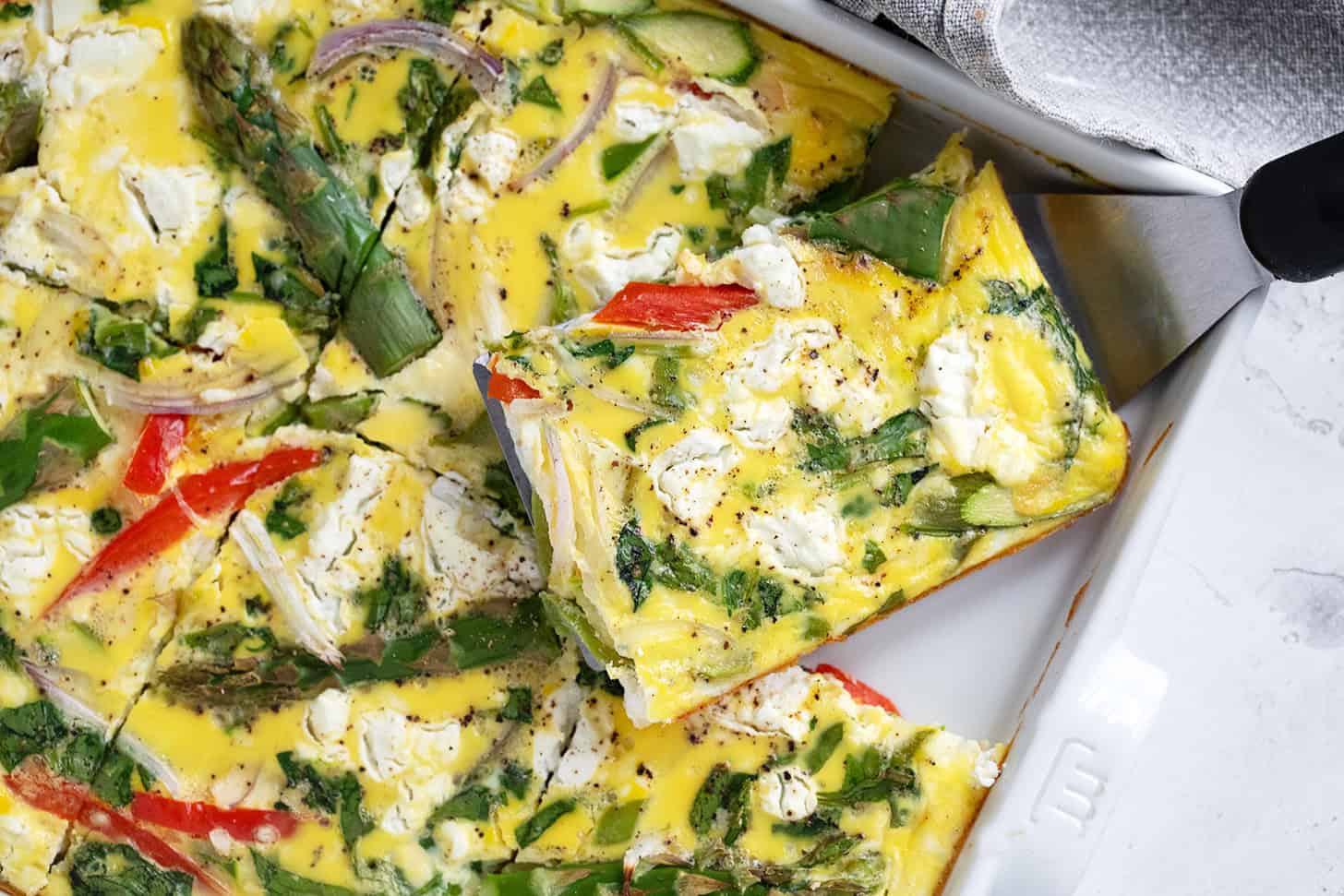 Sheet pan asparagus frittata cut in the pan.