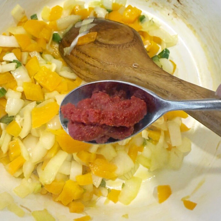 Adding tomato paste to the post with the onion and bell peppers.