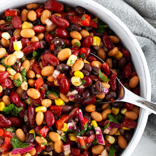 Mexican bean salad in a bowl with a large spoon.