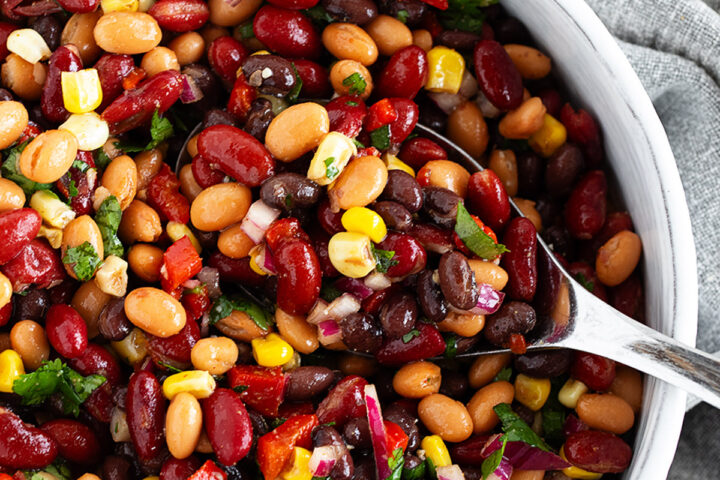 Mexican bean salad in a bowl with a large spoon.
