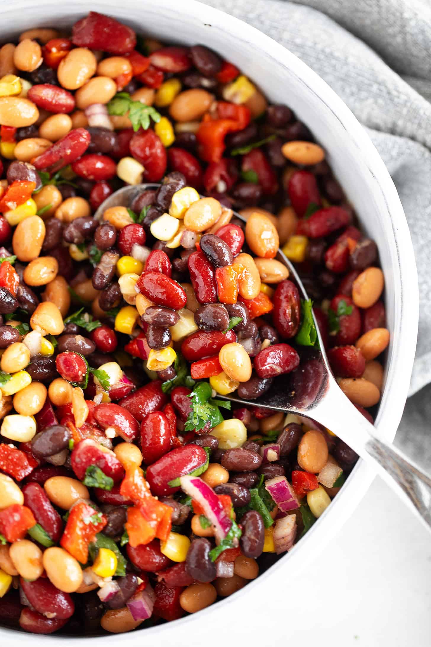 Mexican bean salad in a serving bowl with a spoon.