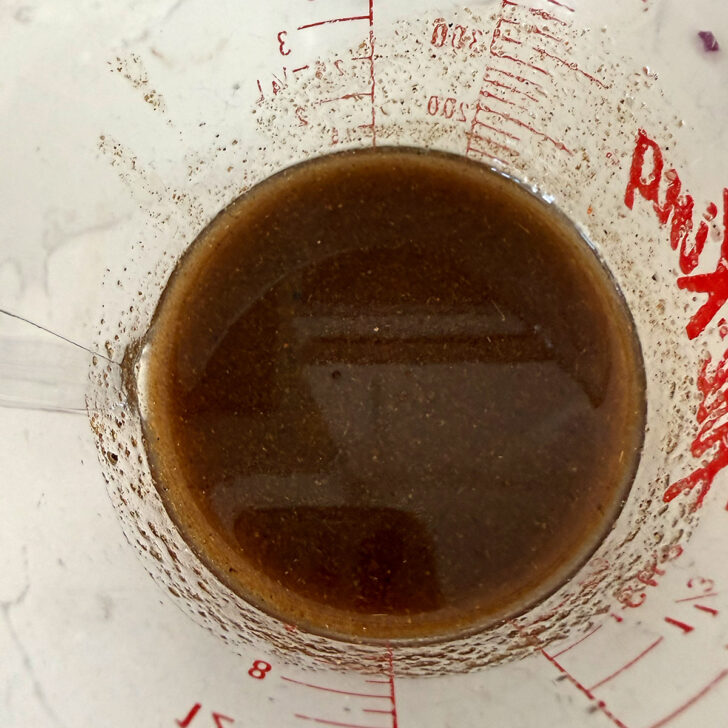 Mexican bean salad dressing mixed up in a measuring cup.