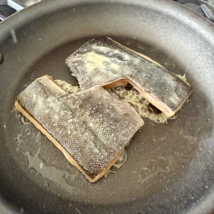 Cooking the black cod in a skillet.