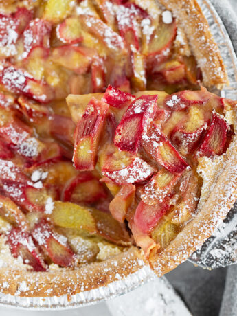 Rhubarb custard pie with a slice on a server.