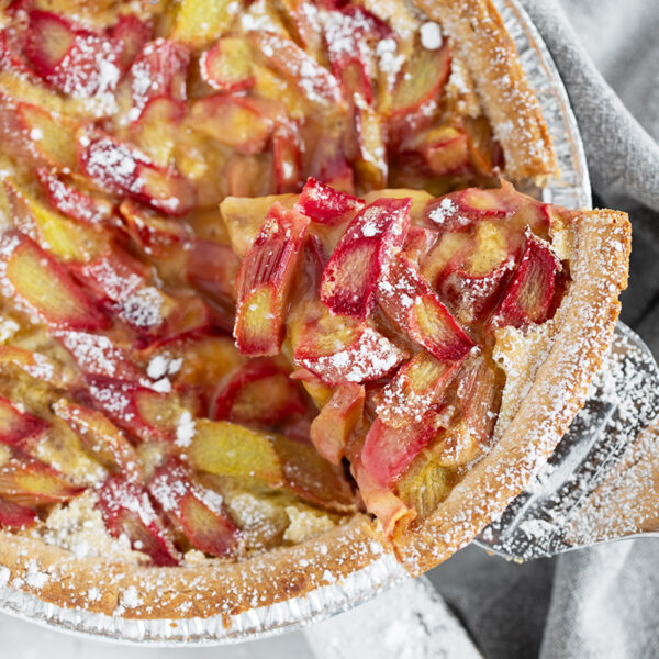 Rhubarb custard pie with a slice on a server.