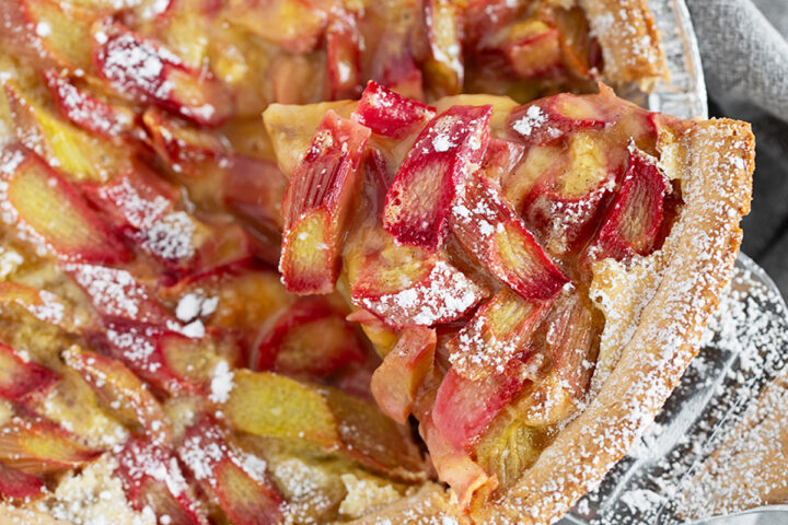 Rhubarb custard pie with a slice on a server.