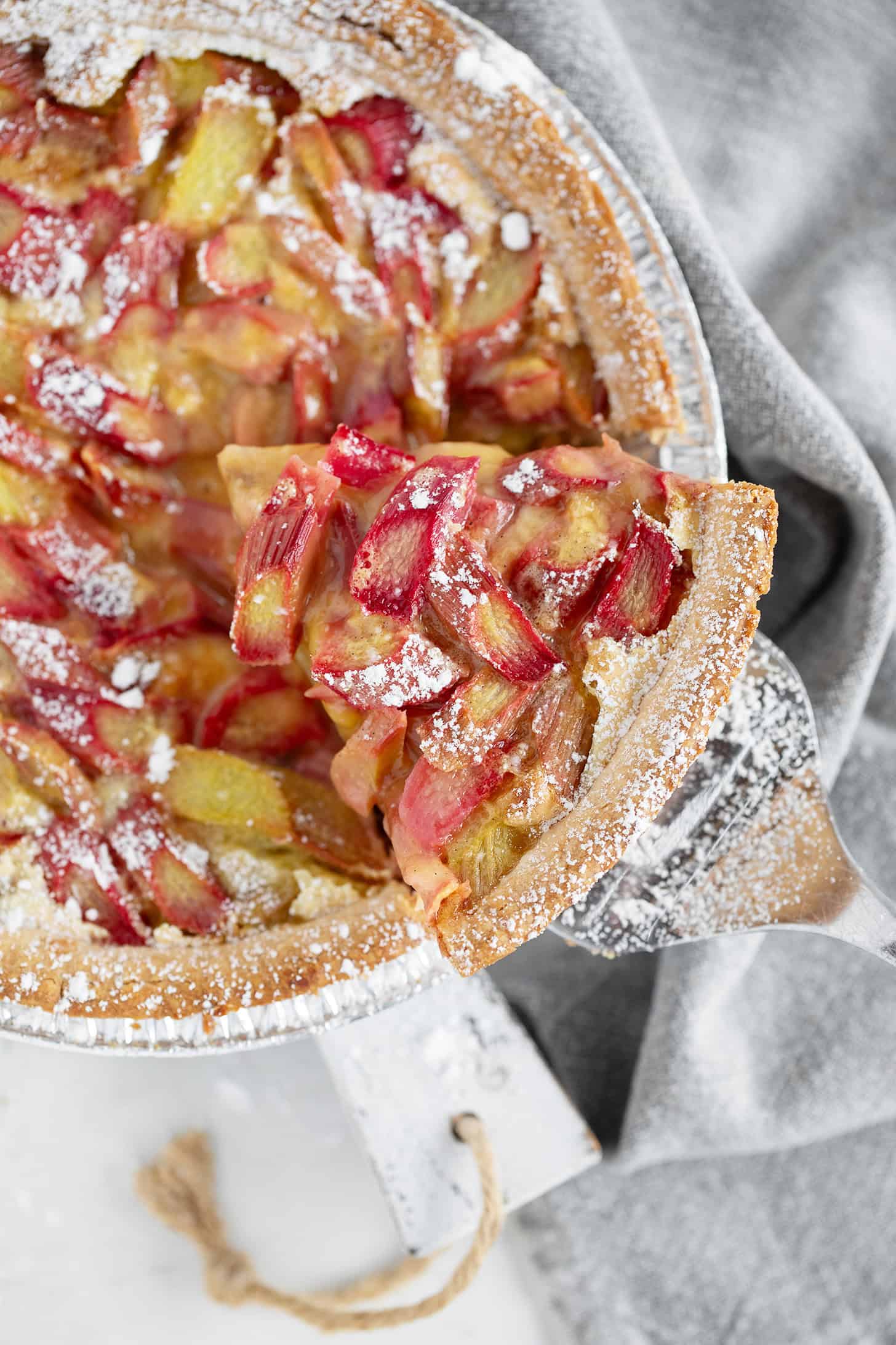 Rhubarb custard pie with a slice on a server.