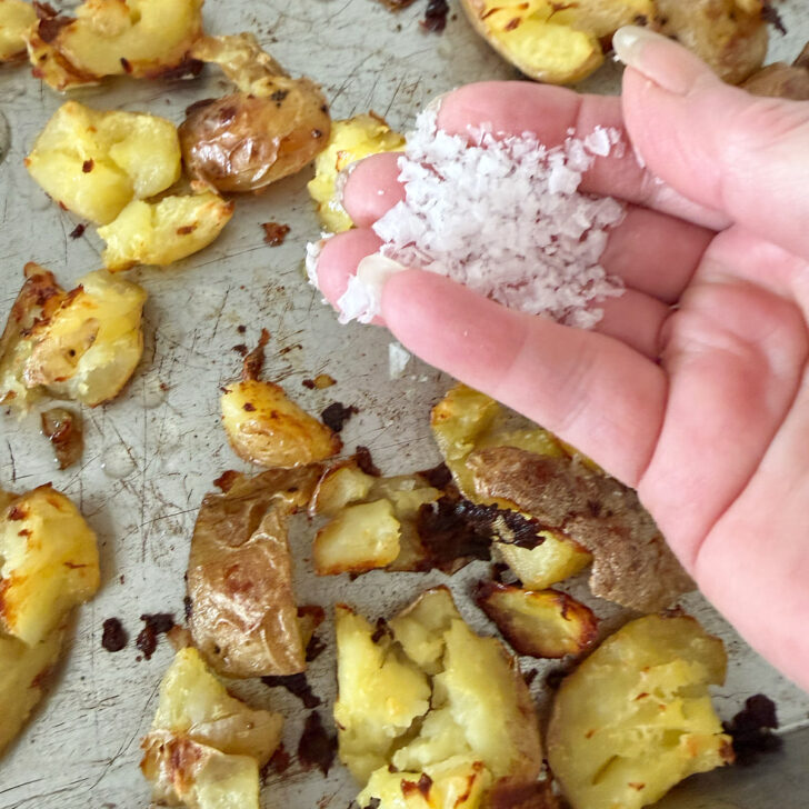 Sprinkling salt on the hot roasted potatoes.