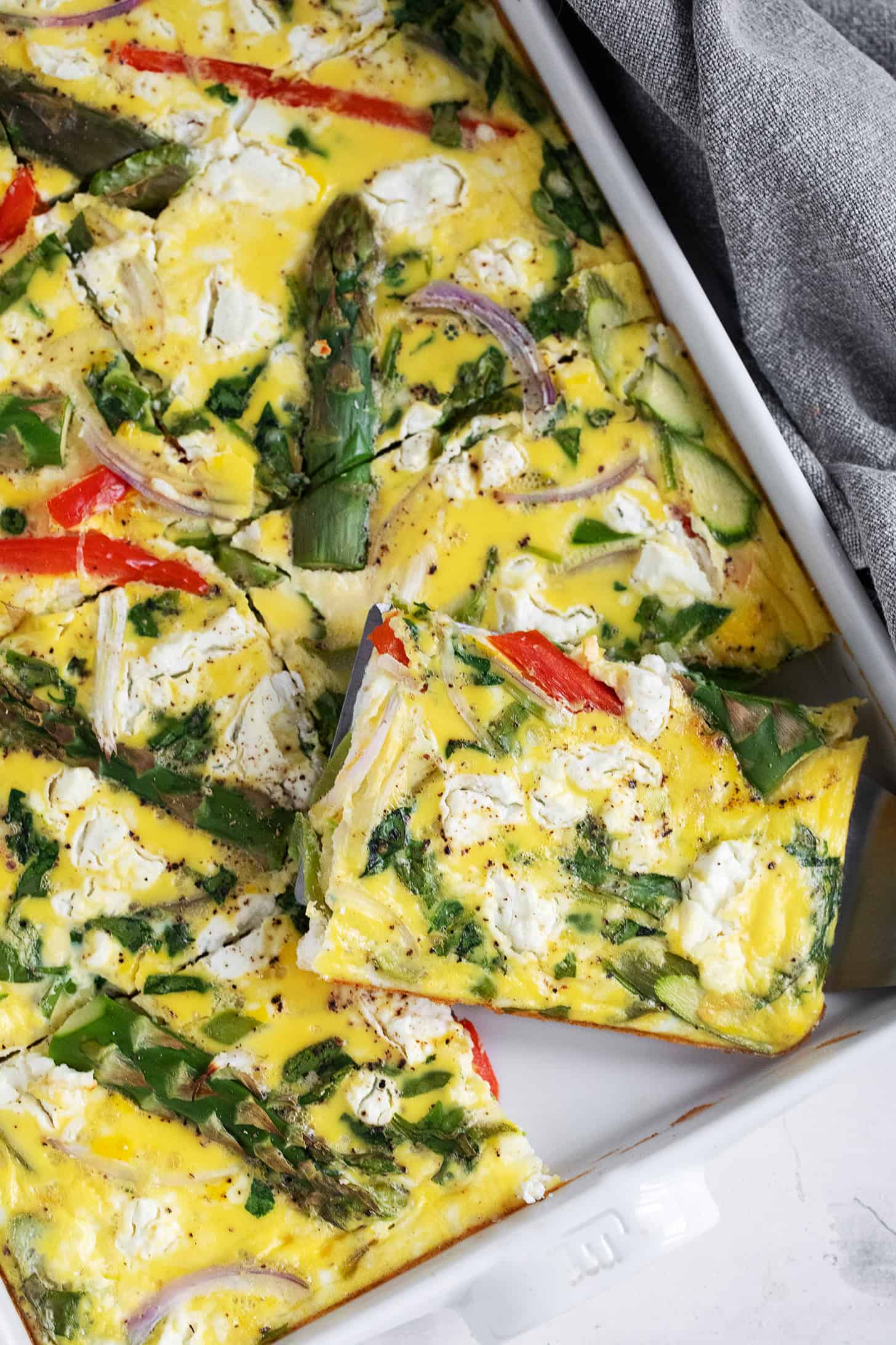 Sheet pan asparagus frittata sliced in the pan.