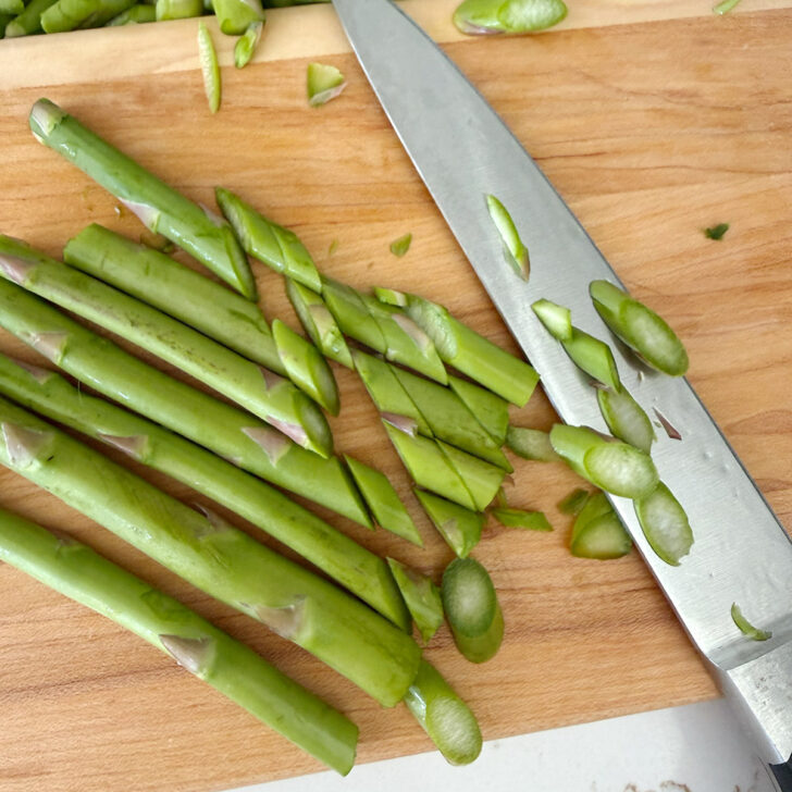 Cutting the asparagus stalks diagonally.