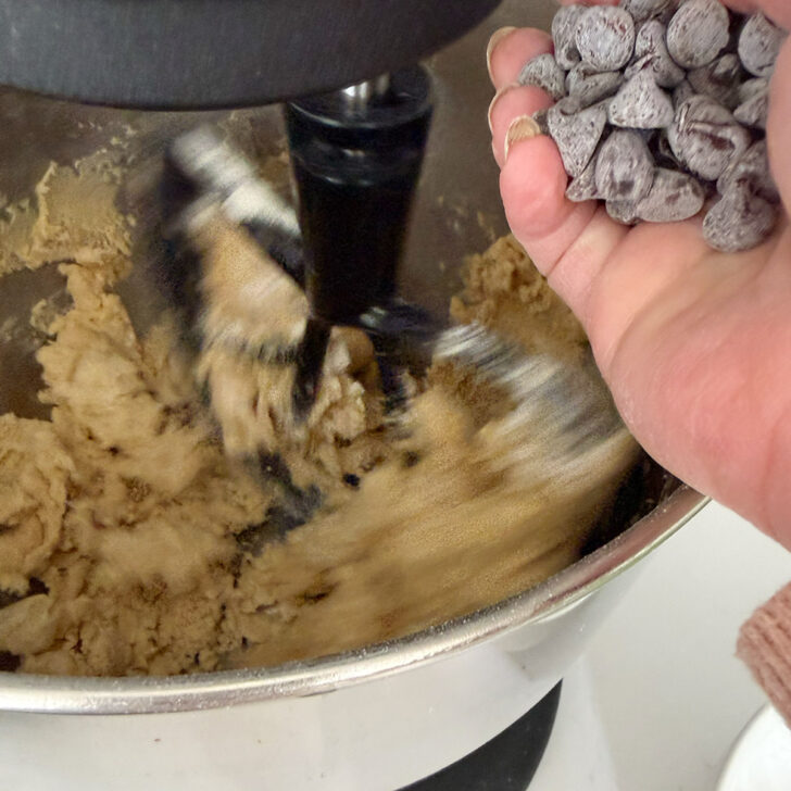 Adding chocolate chips to the cookie dough.