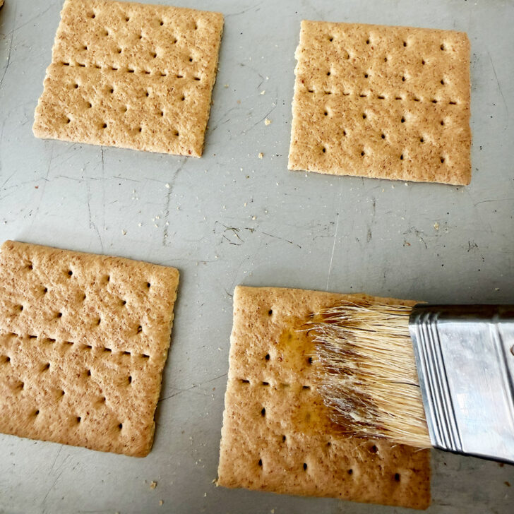 Brushing butter onto the graham cracker squares.